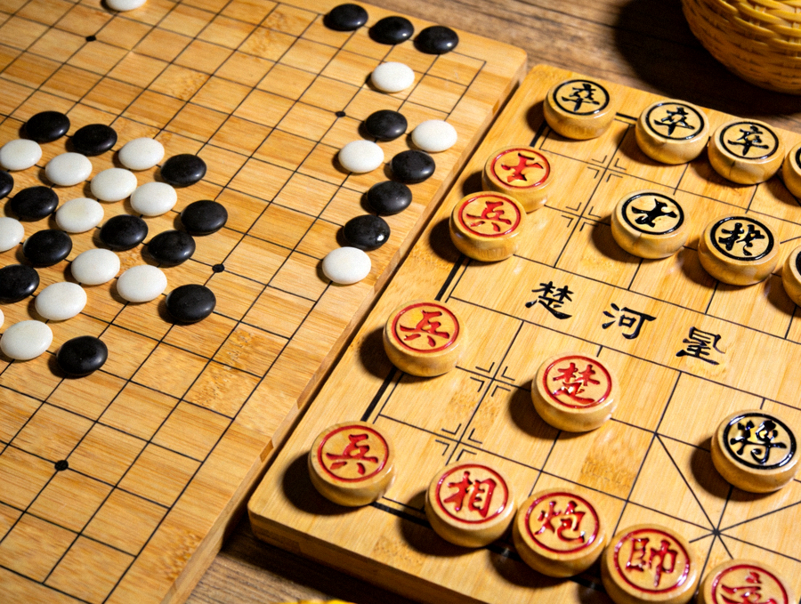 木质棋桌上围棋与象棋棋盘并列摆放的静物画面