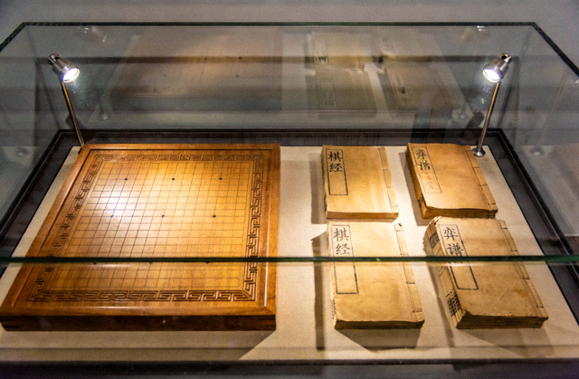 棋牌文化主题展览现场陈列的棋盘与古籍文献